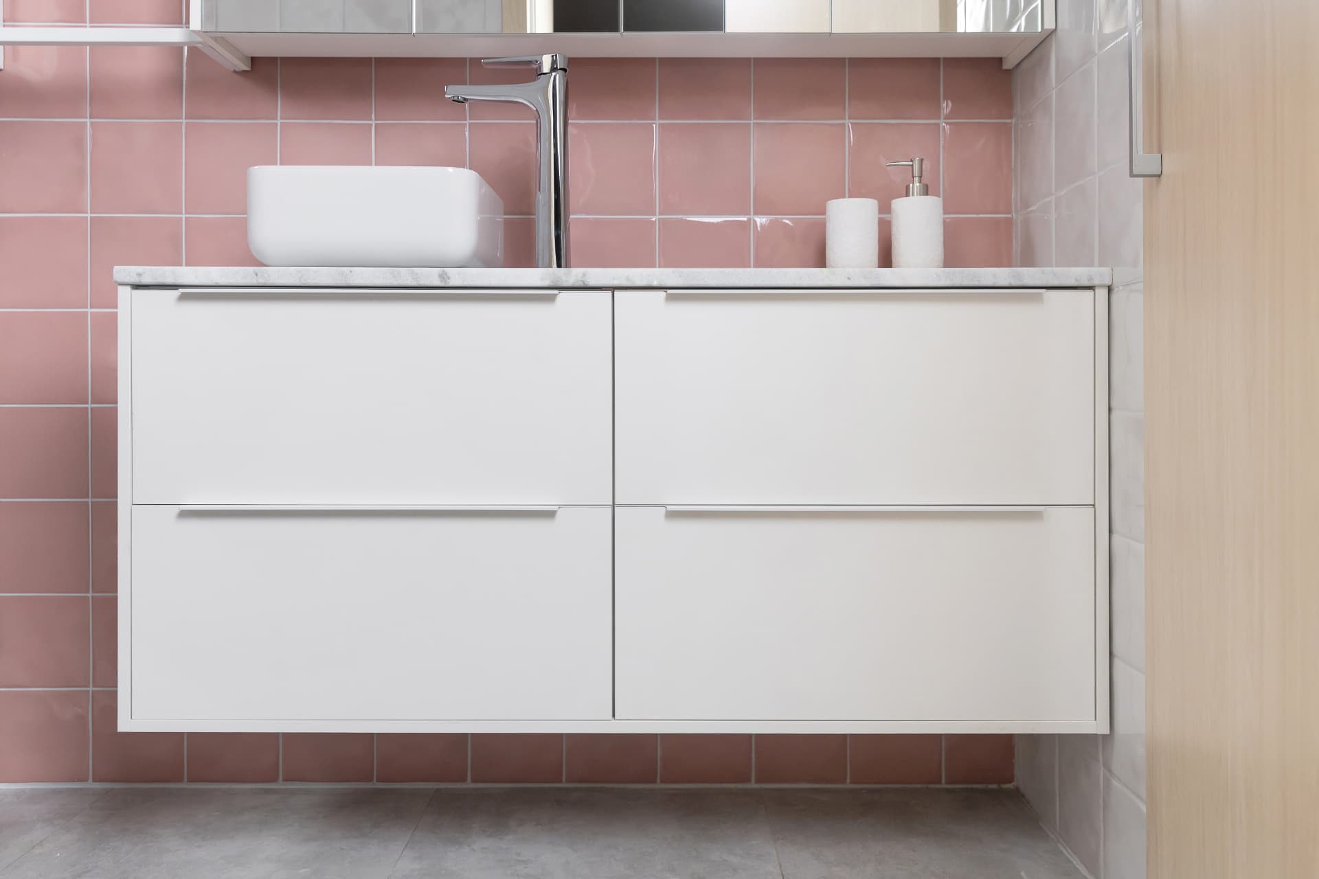 Banheiro clean com gabinete branco e revestimento rosa